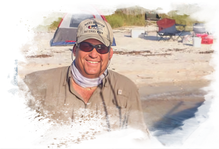 A man wearing a hat and sunglasses on the beach.