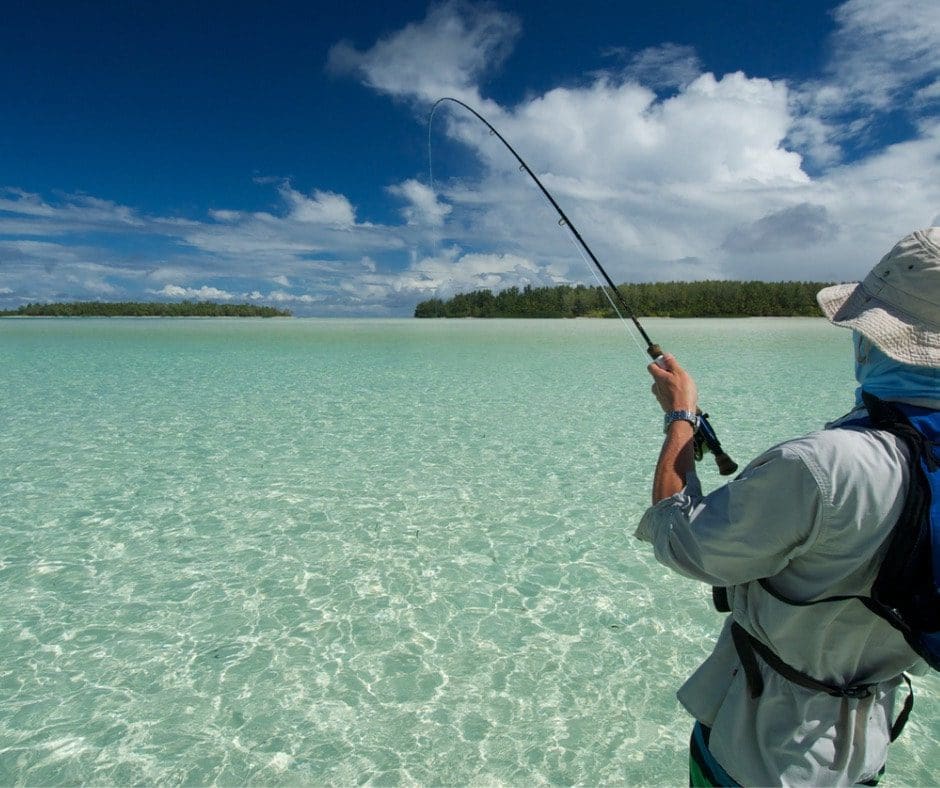 A man in the water holding onto a fishing rod.